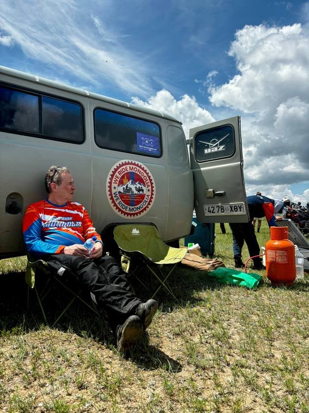 Rider relaxing in a camp chair beside the support van