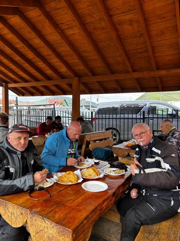 Riders enjoying fried pastries at a roadside shelter